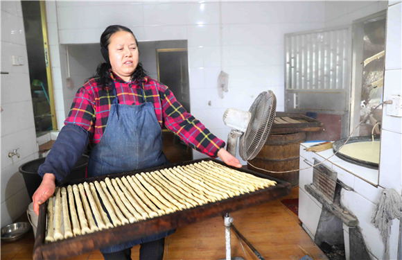 村民把裹好的豆筋端到灶火旁的烘干室去烘干。劉輝 攝