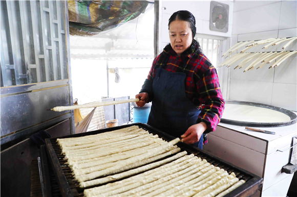 1月27日，梁平區(qū)禮讓鎮(zhèn)同河村8組，村民在把裹好的豆筋放到木箱上。劉輝 攝