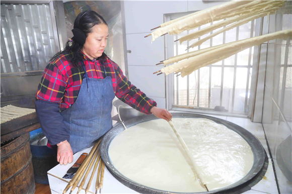 1月27日，梁平區(qū)禮讓鎮(zhèn)同河村8組，村民用竹棍在鐵鍋內(nèi)裹豆筋。劉輝 攝